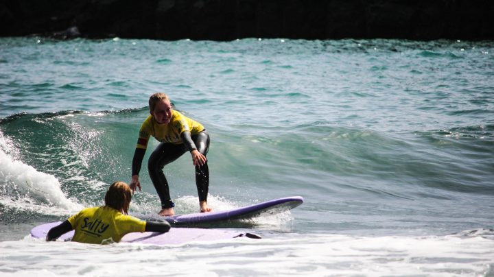 a young girl riding a wave on a surfboard in the water